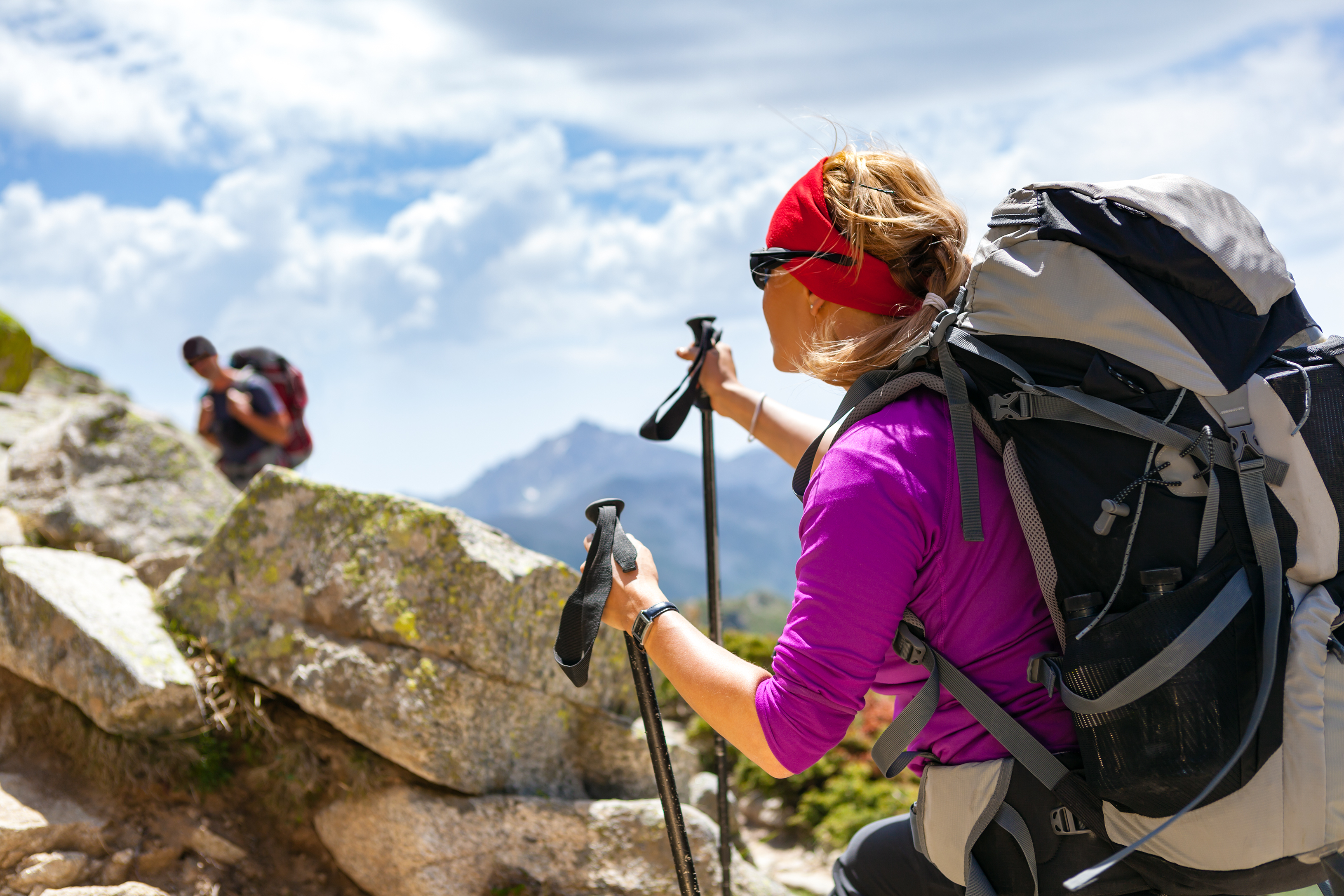 La randonnée en Corse moby_randonnée-corse Une photo d’une femme randonneuse en premier plan et un homme en second plan. La femme est équipée d’un bandeau rouge, de lunettes noires, d’un t-shirt à manche longues violet, d’un sac à dos et de bâtons. 