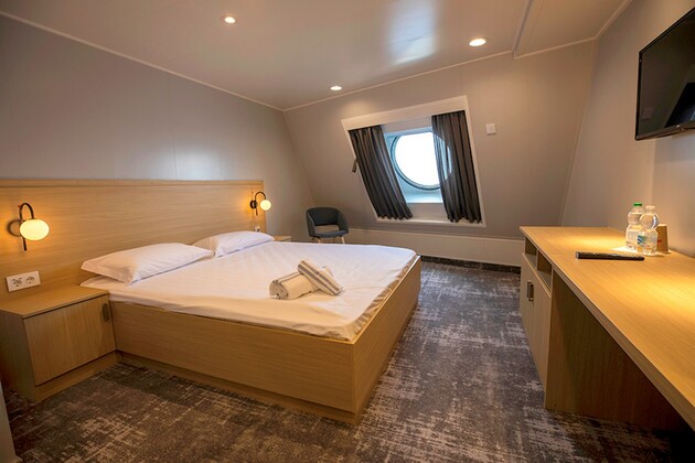 Une cabine pour deux personnes avec un lit double, un bureau et un fauteuil