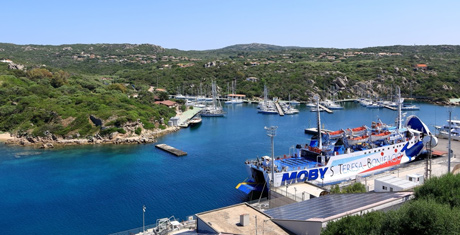 Ferry Moby Lines blanc et bleu au port de Santa Teresa di Gallura en Sardaigne avec en arrière-plan des paysages verdoyants